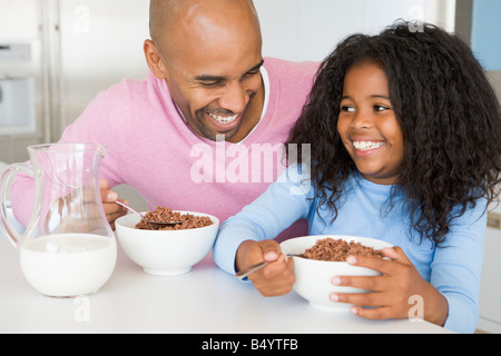 Vater mit Tochter sitzen, als sie sie frühstücken Stockfoto