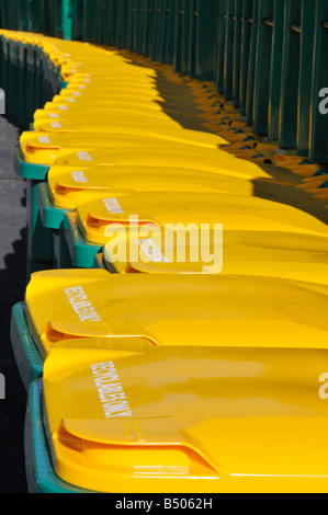 Viele recycling Bins oder Wheelie bins bis in einer Reihe mit leuchtend gelben Deckel ausgekleidet Stockfoto