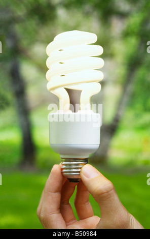 Nahaufnahme von einer Hand hält eine kompakte Leuchtstofflampen-Glühbirne im freien Stockfoto