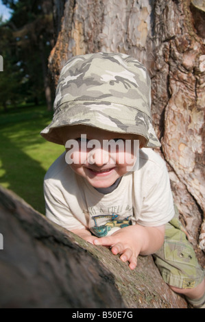 Kind sitzt auf Ast Stockfoto