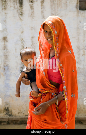 Eine indische Frau Mutter in einem roten Sari, mit ihrem Baby Kind, Rajasthan, Indien Asien Stockfoto