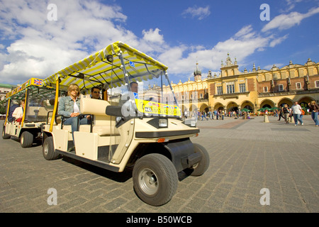 Eine elektrische Auto Stadtrundfahrt im Main Market Square von Krakau mit den Tuchhallen Sukiennice im Hintergrund. Stockfoto