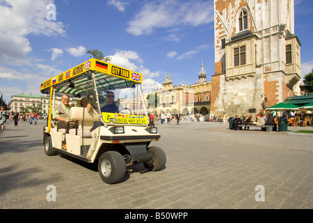 Eine elektrische Auto Stadtrundfahrt im Main Market Square von Krakau in Polen mit der Basis der Rathausturm rechts. Stockfoto