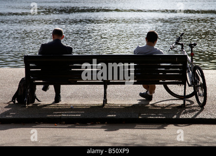 Zwei Männer sitzen auf einer Bank auf dem Serpentine River in Hyde Park, London Stockfoto