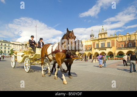 Ein Tourist Pferdekutsche im Main Market Square von Krakau in Polen mit den Tuchhallen Sukiennice hinter rechts. Stockfoto