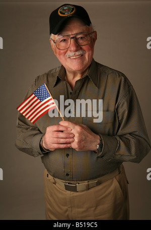 Ältere amerikanische Veteranen des zweiten Weltkriegs halten eine amerikanische Flagge und eine United States Army Kappe trägt. Stockfoto