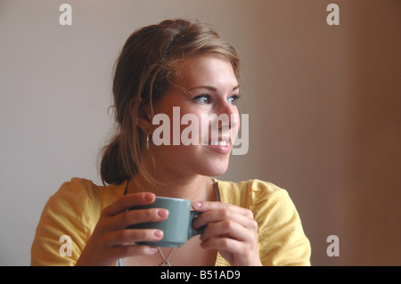 Eine junge Frau hat ein heißes Getränk in der Hand während der Gespräche. Stockfoto