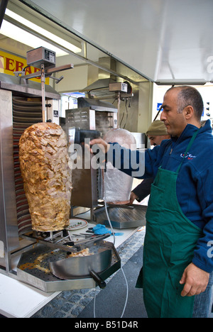 Mann schnitzen Fleischscheiben von einer Rolle vom Lamm gegrillt zu Döner Kabob Stockfoto