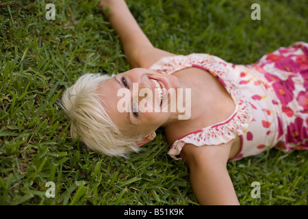 Frau, lachen und liegen auf dem Rasen Stockfoto