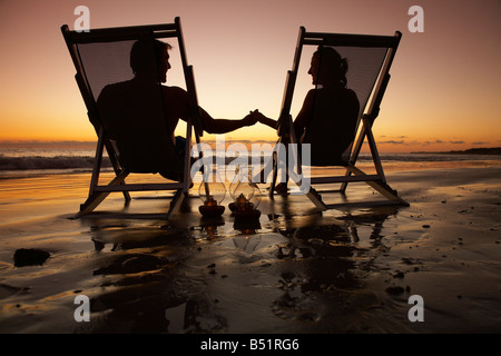 Paar, sitzen in Liegestühlen am Strand bei Sonnenuntergang, Mexiko Stockfoto