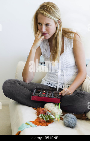 Junge Frau sitzt auf dem Sofa Stockfoto