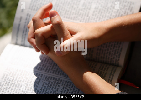 Hände gefaltet auf aufgeschlagene Bibel hautnah Stockfoto