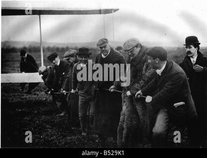 Die Zeitung Baron Lord Northcliffe 1909 trug den Pelzmantel und der ehemalige britische Premierminister Arthur Balfour, die dazu beitragen, um das Flugzeug der Gebrüder Wright in Position zu schleppen, denn einem Demonstrationsflug in Pau in Frankreich Herr Orville Wright gesehen werden kann tragen der Bowler Hut Regie Operationen hinter dem Mann Stockfoto