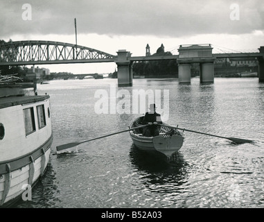 Jeden Tag Charlie Backhouse Zeilen auf dem Fluss Shannon, Athlone, wo er in der Druckerei tätig ist, funktioniert Transport Ruderboot Menschen alte Brücken Wasser Wasserstraße Circa 1960 Stockfoto