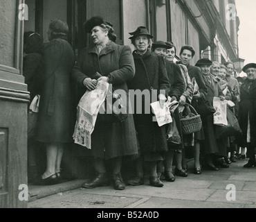 Post Krieg Lebensmittel Rationierung während des zweiten Weltkriegs 1939-45 gab es eine Menge des Mangels an wesentlichen Lebensmittel, die nicht nur Luxus Lieferungen begonnen, kurz geworden und einige Elemente nicht möglich, um vor allem Importwaren wie Tee Bananen Orangen und Trauben zu erhalten war es sechs oder sieben Jahre zuvor keine Früchte galten dann wieder butter Schmalz Süßigkeiten Kuchen Mehl und Zucker wurde schwer zu gefolgt von Fleisch und Fisch, die unser Bild Hausfrauen zeigt Schlangestehen für Fische mit Zeitungspapier wickeln Sie ihre Einkäufe in Shopping Warteschlangen Speisefische Circa 1946 Stockfoto