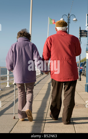 Ein älteres Ehepaar zusammen spazieren Hand in der hand auf Aberystwyth promenade auf ein Herbstnachmittag wales UK Stockfoto