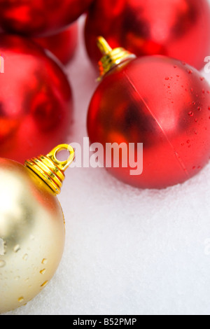 roter und goldener Christbaumschmuck im Schnee Stockfoto