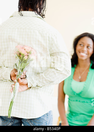 Afrikanischer Mann überraschend Frau mit Blumen Stockfoto