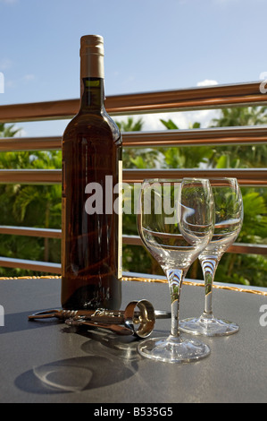 Eine ungeöffnete Flasche Wein und zwei leere Gläser an einem leeren Tisch in einem Restaurant im Freien aus der Nähe Stockfoto