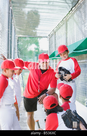 Multi-ethnischen jungen in Baseball Uniformen mit Trainer im Einbaum Stockfoto