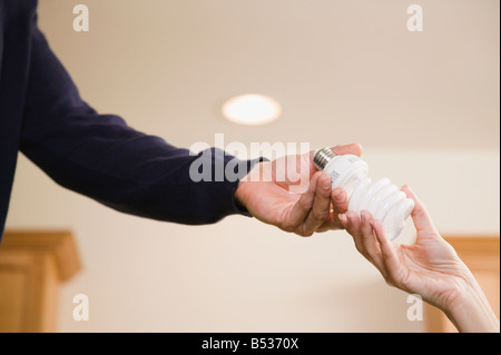 Hispanic Mann Übergabe Frau kompakte Leuchtstoff Glühlampe Stockfoto