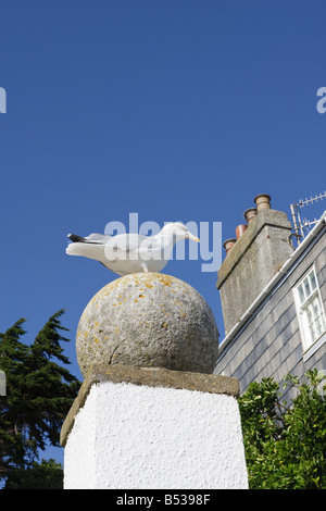 Eine Möwe Sitzstangen auf einem Stein Kugel Säule bei Lyme Regis Dorset gegen ein Deep Blue Sky Stockfoto