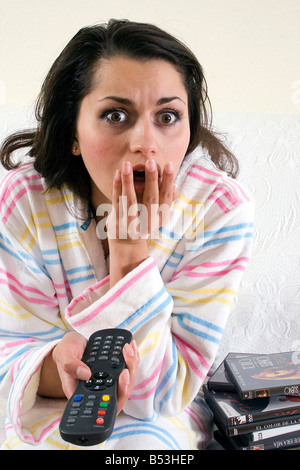 junge Frau mit entfernten gerade etwas komisch oder schockierend im Fernsehen Stockfoto