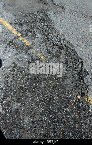 Bröckelnden gebrochen Asphaltdecke mit gelben Linie. Stockfoto