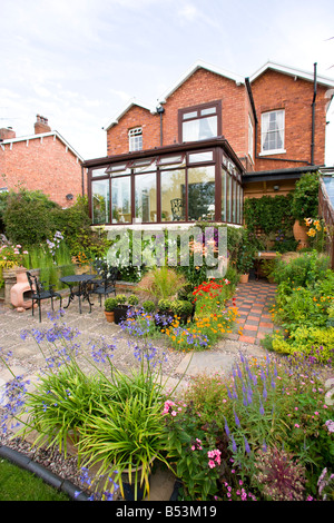 Rückseite des großen Einfamilienhaus mit Wintergarten und gut bepflanzten Garten Stockfoto