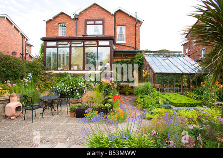 Rückseite des großen Einfamilienhaus mit Wintergarten und gut bepflanzten Garten Stockfoto