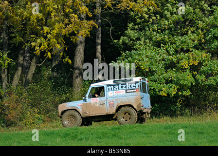 Trüben Sie Licht blaue Land Rover Defender 90 fahren eine Forststraße in das Weserbergland. Stockfoto