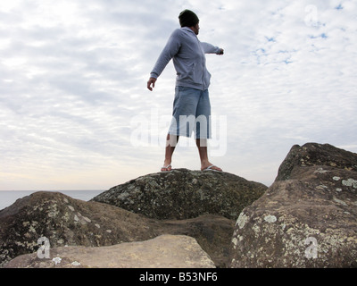 Junger Mann stehen auf Felsen zeigen Stockfoto