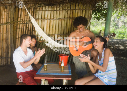 Freunde hören Mann spielen Gitarre Stockfoto