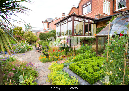 Rückseite des großen Einfamilienhaus mit Wintergarten und gut bepflanzten Garten Stockfoto