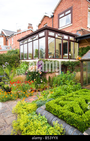 Rückseite des großen Einfamilienhaus mit Wintergarten und gut bepflanzten Garten Stockfoto