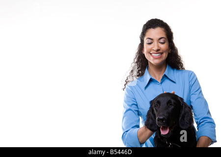 Frau spielt mit einem schwarzen Hund auf weißem Hintergrund Stockfoto