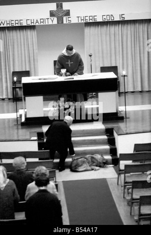 Hunde Tiere humor Religion: "Schatten" der elsässischen ihrem Meister - Pfarrer Dom Edmund Jones - überall er geht folgt, selbst wenn er die Messe in der Kirche Christkönig, Cockfosters, sagt Schatten ist direkt hinter ihm. Sie folgt ihrem Meister in der Kirche und liegt ruhig am Fuße der Wallfahrtskirche Schritte unter dem Altar und befindet sich direkt hinter ihm, wenn der Dienst beendet ist. Dom Edmund hat sogar Sonderwünsche, dass der Hund Hochzeitsservice eingeladen werden, und die Kinder gehen in die Kirche, den Hund zu sehen. Schatten, ruhig auf der Treppe unter dem Altar liegen. November 1969 Z10753-002 Stockfoto