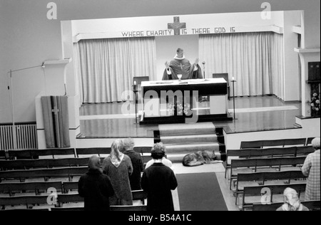 Hunde Tiere humor Religion: "Schatten" der elsässischen ihrem Meister - Pfarrer Dom Edmund Jones - überall er geht folgt, selbst wenn er die Messe in der Kirche Christkönig, Cockfosters, sagt Schatten ist direkt hinter ihm. Sie folgt ihrem Meister in der Kirche und liegt ruhig am Fuße der Wallfahrtskirche Schritte unter dem Altar und befindet sich direkt hinter ihm, wenn der Dienst beendet ist. Dom Edmund hat sogar Sonderwünsche, dass der Hund Hochzeitsservice eingeladen werden, und die Kinder gehen in die Kirche, den Hund zu sehen. Schatten, ruhig auf der Treppe unter dem Altar liegen. November 1969 Z10753 Stockfoto