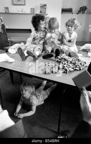 Weg von der der Masse dieses Kind Modell verbirgt sich unter dem Tisch; es handelt sich um eine hübsche Feder für Kinder bei Tick-A-Tee mit einem s Stockfoto
