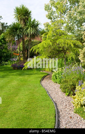 Großen gestreiften Rasen mit Cordyline und geschwungenen Kiesweg. Stockfoto