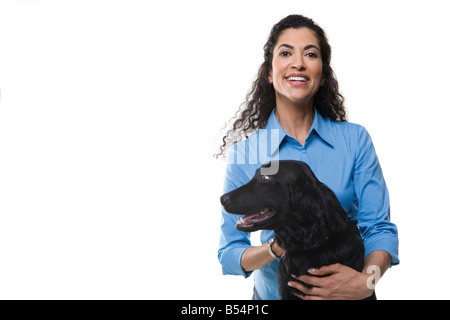 Frau spielt mit einem schwarzen Hund auf weißem Hintergrund Stockfoto