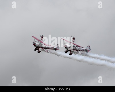 Zwei Flügel zu Fuß Stunt Frauen verrichten ihre Routine gegen einen dunklen Gewitterhimmel während einer Sommerausstellung bei einer airshow Stockfoto