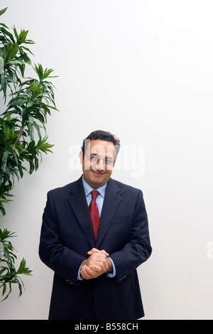 Business-Mann stehend im Büro mit Händen zusammen auf der Suche zufrieden Stockfoto