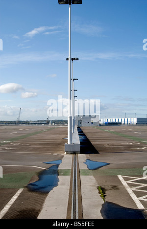 Eine Reihe von Laternenmasten auf der obersten Ebene von einem leeren Parkplatz in Southampton mit Pfützen, blauer Himmel und Wolken Stockfoto