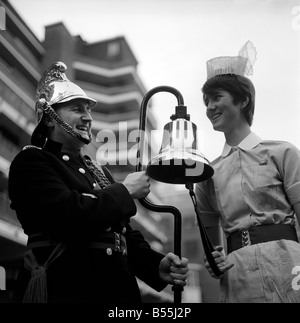 21 jährige Krankenschwester, ging Angela Wyatt vom St. Thomas Hospital in die Londoner Feuerwehr Hauptquartier, Lambeth, eine Feuerglocke zu sammeln, die auf Leihbasis für The Malcolm Sargent Cancer Fund für Kinder, wollte Christmas Carol-Konzert in der Festhalle. Die Feuerglocke mit führenden Feuerwehrmann Joe Wills ausprobieren, ist Krankenschwester Angela Wyatt. Dezember 1969 Z12149 Stockfoto