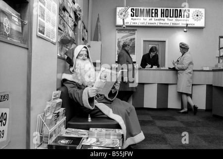 Weihnachten Humor: 75 Jahre alte Samuel Johnson der Weihnachtsmann Gamages, verbrachte seine Mittagspause heute, auf der anderen Straßenseite in Holborn, durchblättern Sommer Broschüren in einem Reisebüro - träumen von der Sonne. Kurz darauf gab er wieder Geschenke für die Kinder. Dezember 1969 Z12331 Stockfoto