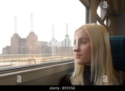 eine schöne blonde Frau auf eine britische Schiene Zug vorbei an der Battersea-Kraftwerk in London-Südengland Reisen Stockfoto