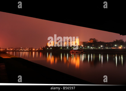 Blick auf den berühmten Wawel-Schloss in der Nacht, spiegelt sich in der Weichsel. Foto unter einer Brücke in Krakau, Polen Stockfoto