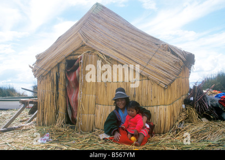 einheimische Mädchen und ihre kleine Schwester saß eine Hütte aus Schilf auf einer Uro-Insel in der Nähe von Puno aus Stockfoto