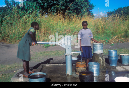 Mädchen, die Wasserpumpen an eine Wasserpumpe in einem Dorf am Lake Malawi, Afrika Stockfoto